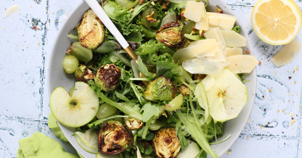 A green salad featuring grapes, granny smith, brussel sprouts, lemon, salt, and pepper.