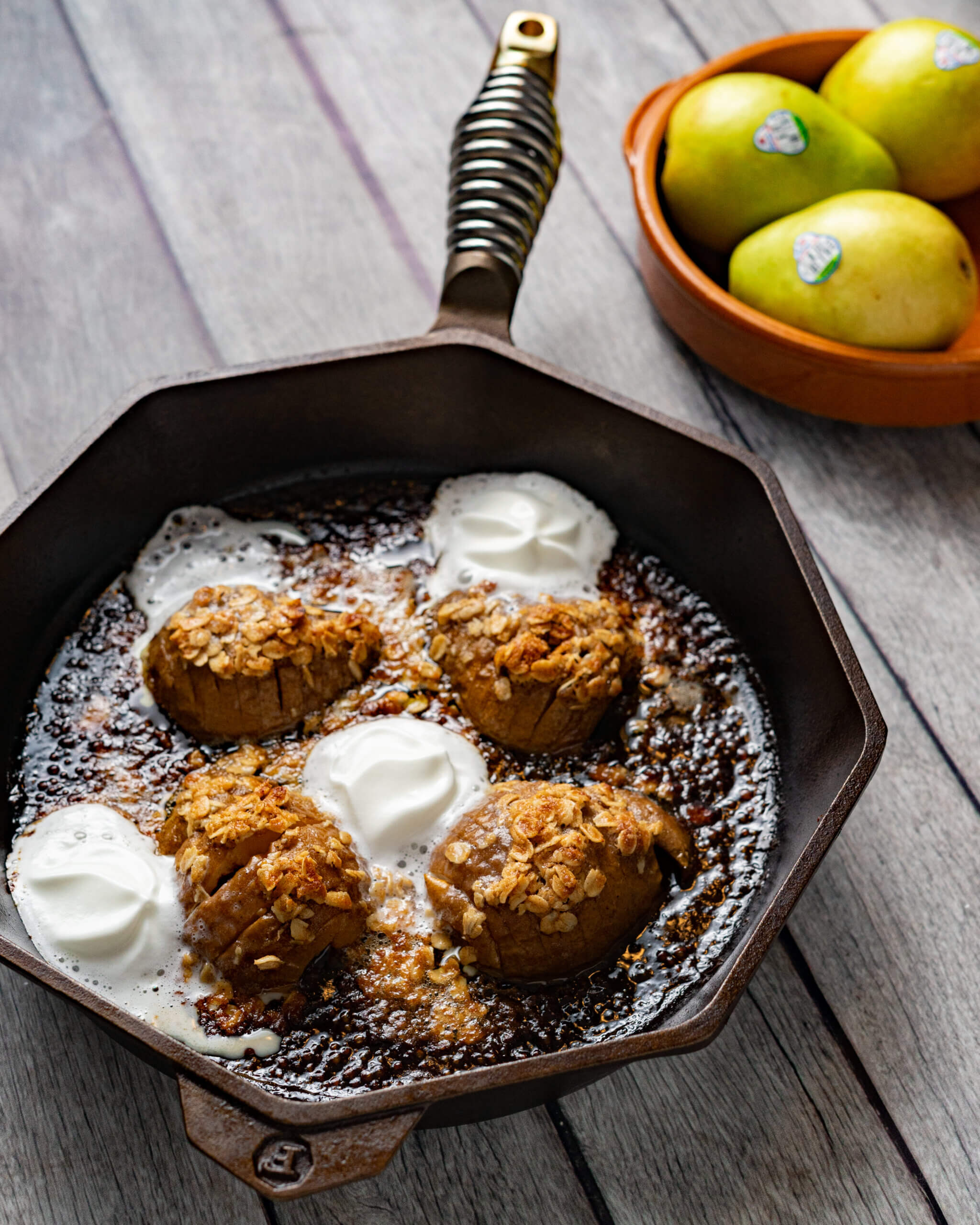 Hassetlback pears in a cast iron pan with ice cream dollops.