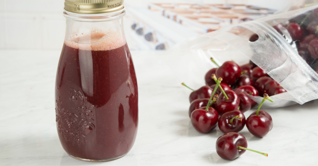 Cherry juice with cherries in the background