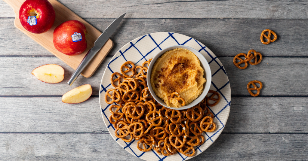 Apple butter hummus served in a bowled with a plate of pretzels