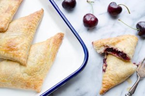 Cherry Turnovers on serving dish with cherries near by on counter