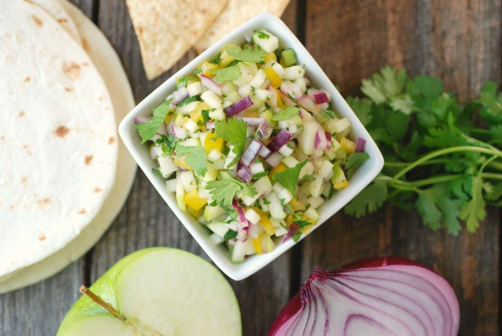 Green Apple Salsa in a bowl next to various ingredients