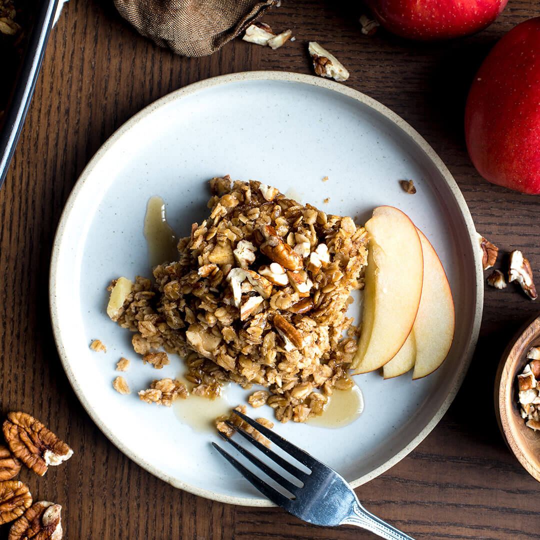 Baked oatmeal with apples and pecans on a plate.