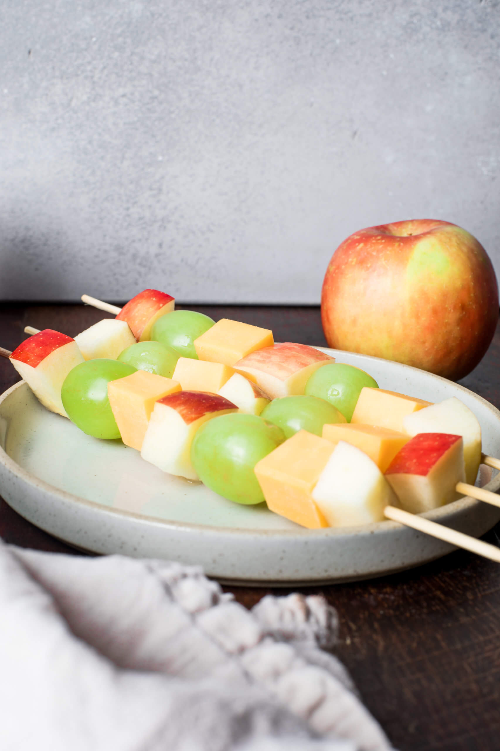 Fruit kabobs with apples, grapes, cheese, on a serving plate.