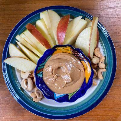 Sliced apples with peanut butter and nuts on a plate