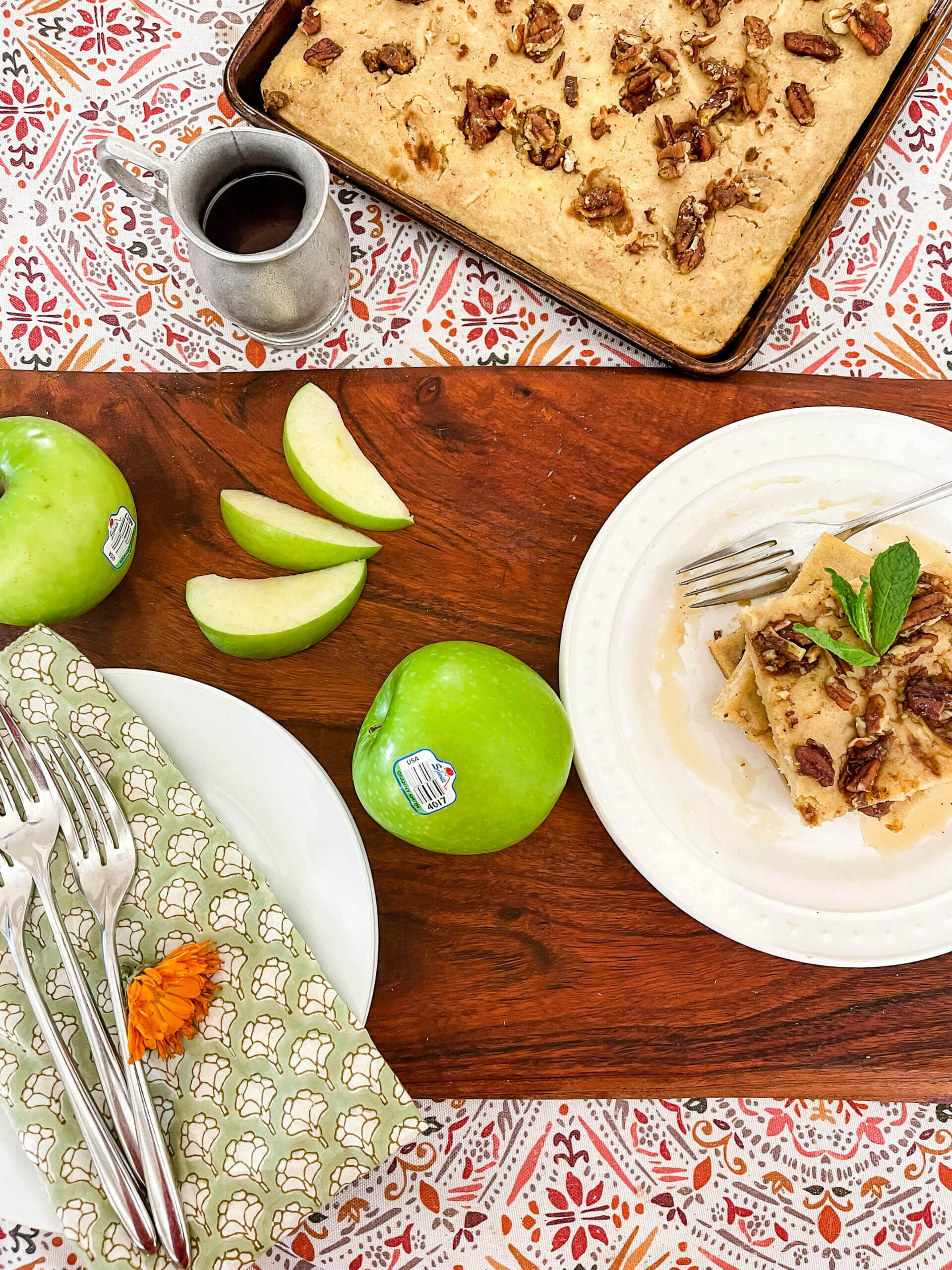 A serving of sheet pan apple pancakes with granny smith apples and an extra plate in the foreground