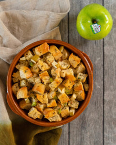 Stuffing in a bowl with a granny smith beside it.