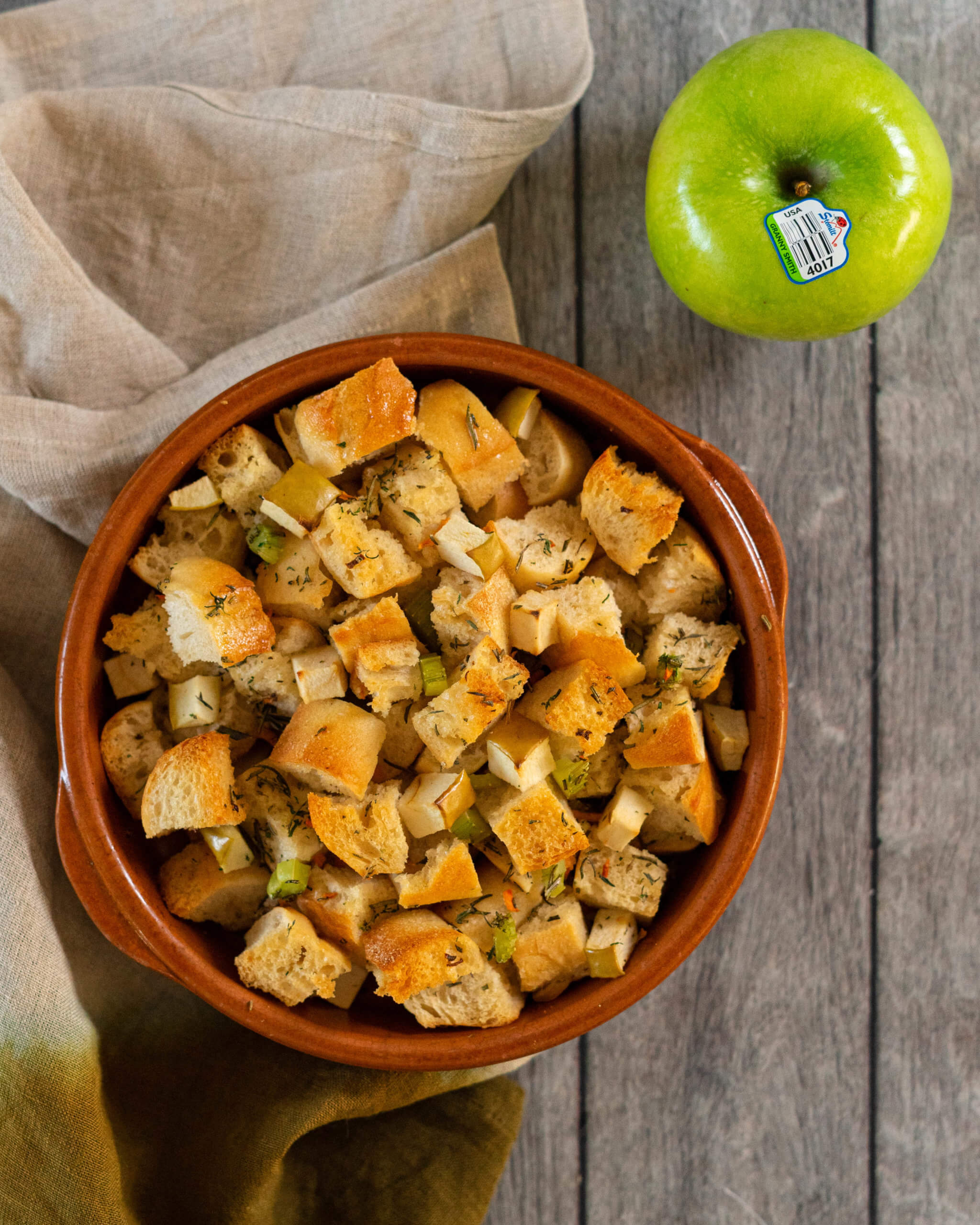 Sourdough stuffing in a bowl with a granny smith apple beside it.