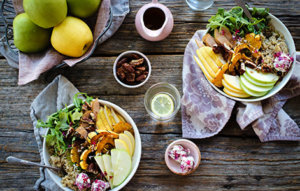 two dishes of harvest Buddha bowls on wood table