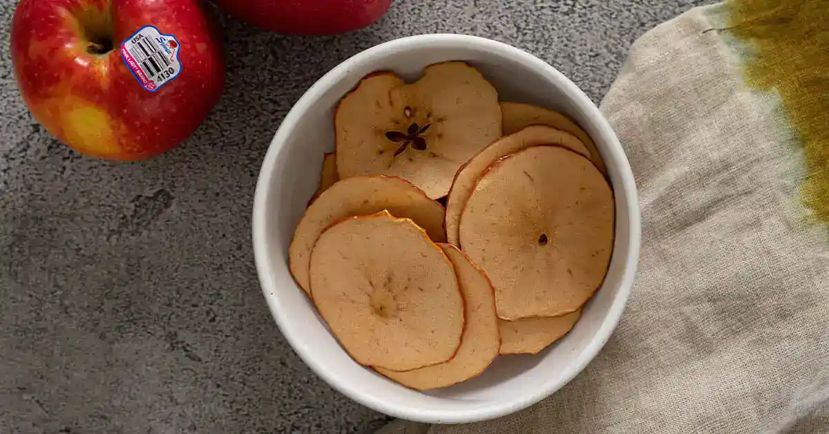Dried apple slices in a white bowl for dehydration process.