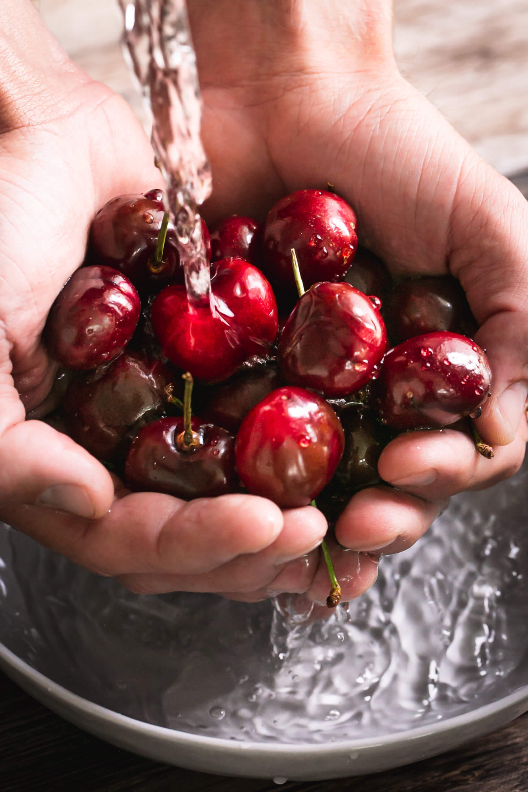 A handful of cherries being rinsed under water
