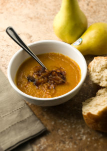 bowl of crock pot squash and pear soup with pears in the background