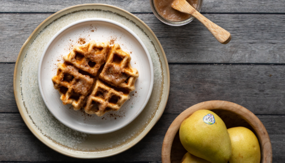 A plate of waffle with pear butter and pears in bowl next to the waffles