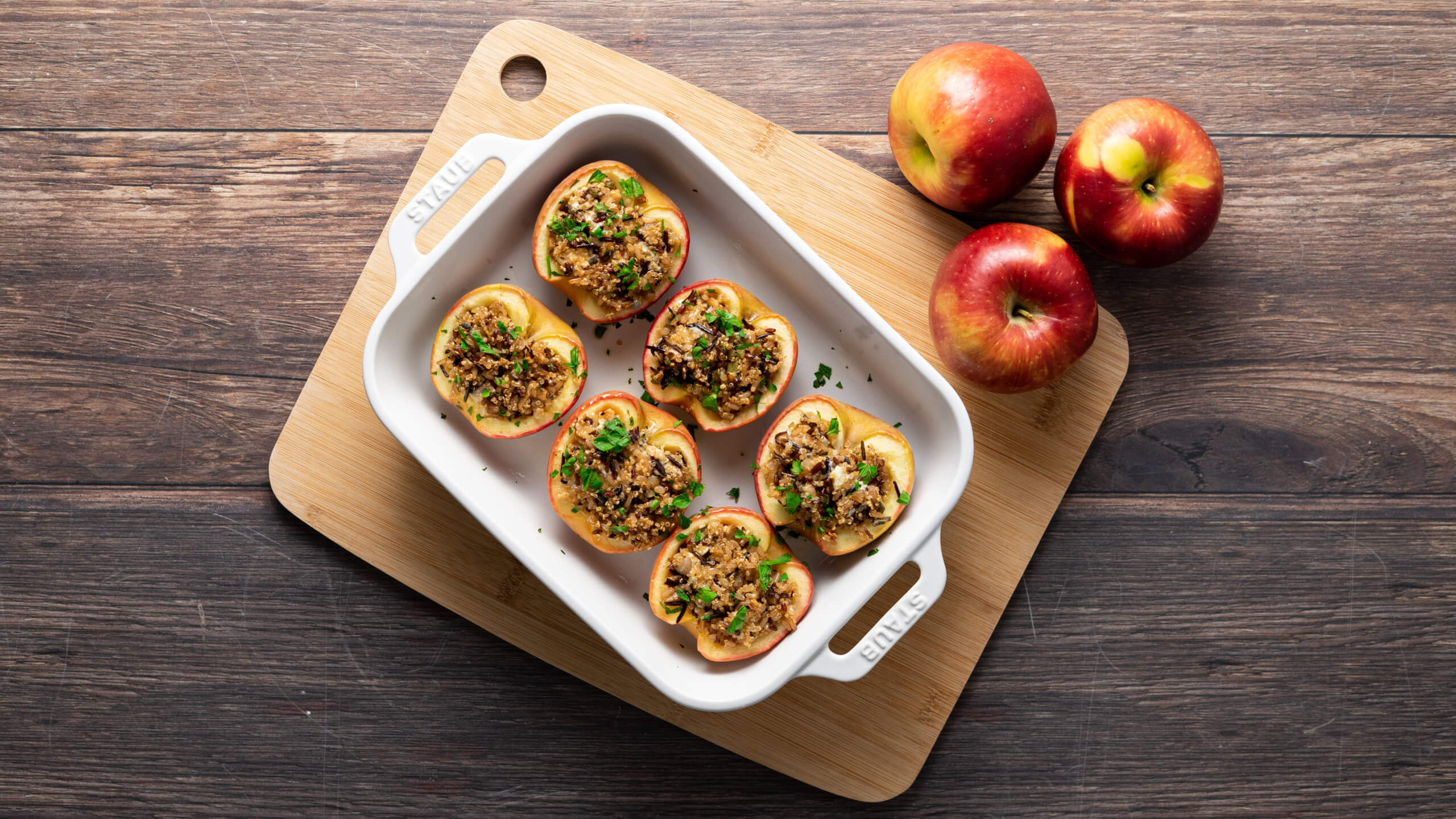 stuffed apples in a baking dish on a cutting board