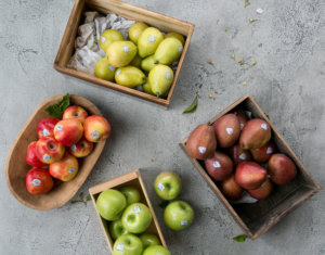 Apples and pears in fruit bowls and square boxes on a concrete counter top