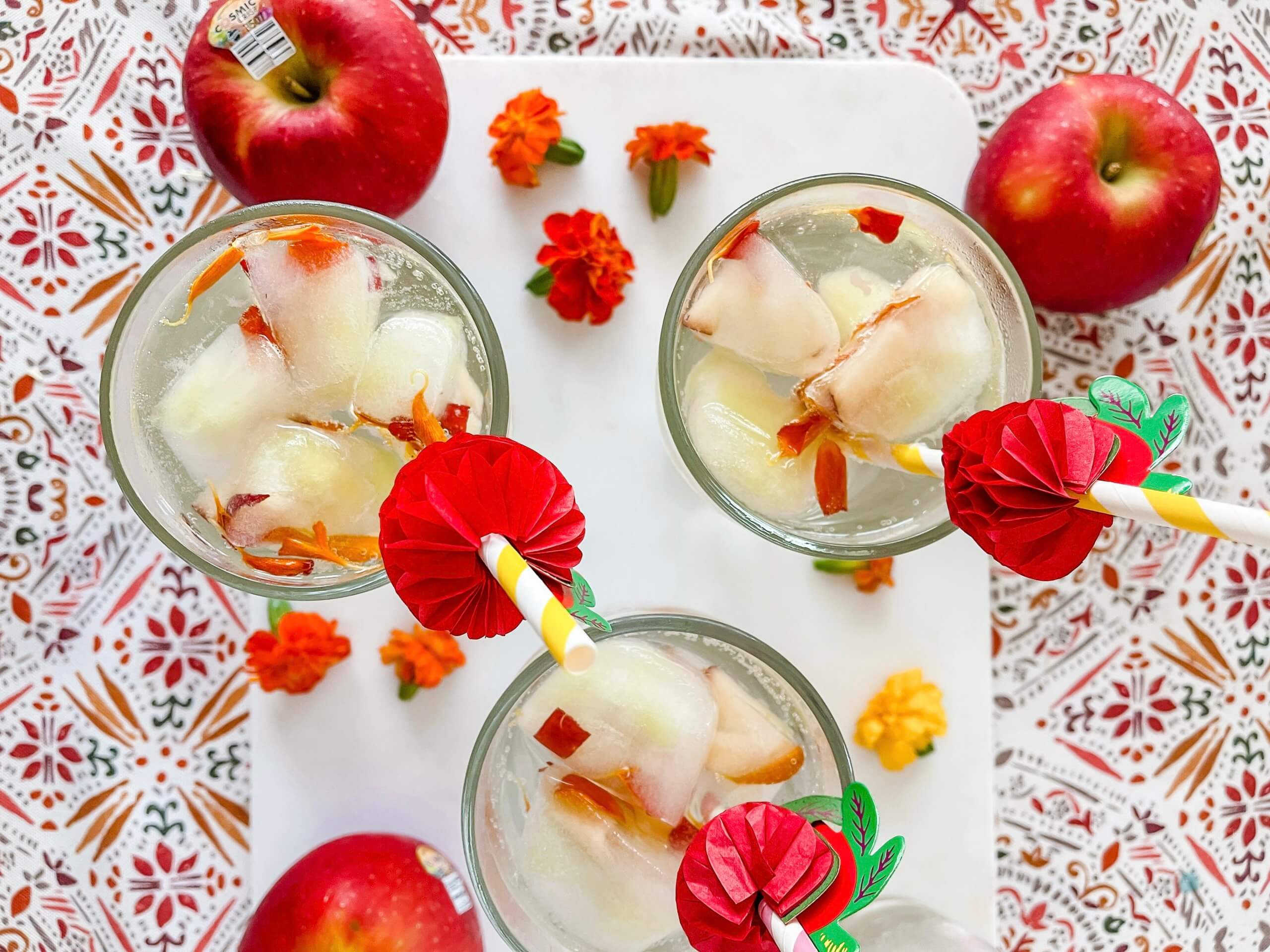 Cosmic Crisp apples and glasses filled with water and Apple Blossom fruit ice cubes.