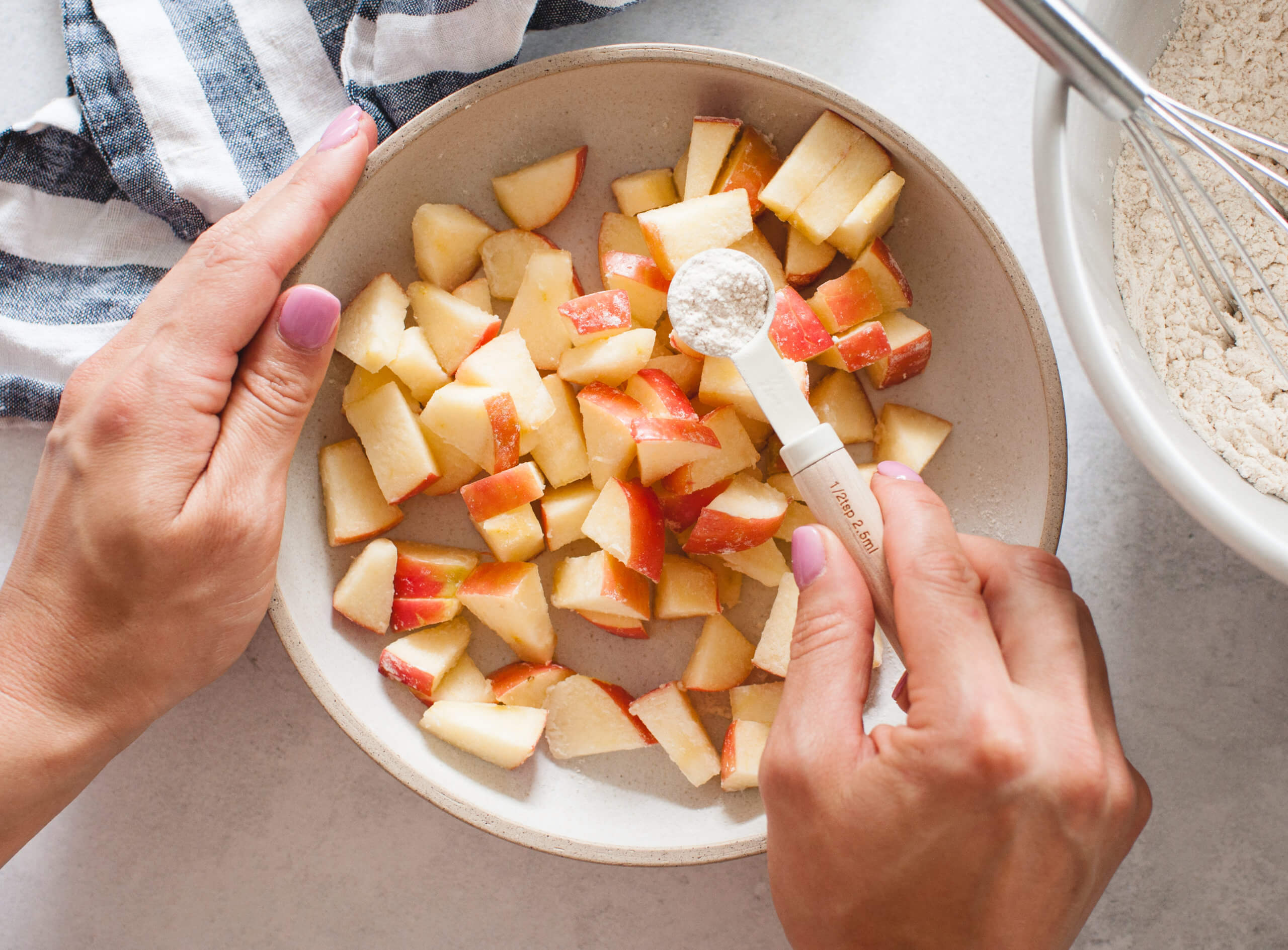 cut apple pieces being tossed in flour