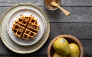 Pear butter on a waffle with pears in the background