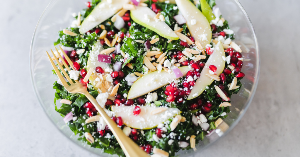 A tossed kale, pear, and goat cheese salad ready to eat.