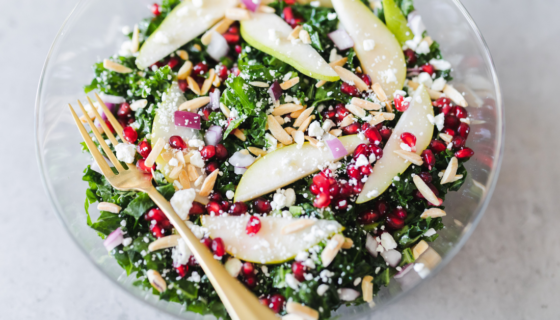 A tossed kale, pear, and goat cheese salad ready to eat.