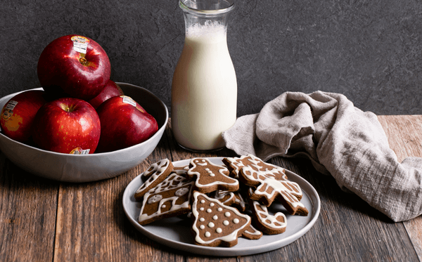 Apple Gingerbread Cookies on a plate with apples, milk, and a rag in the background.