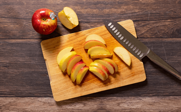 Apple slices on a cutting board with a knife.