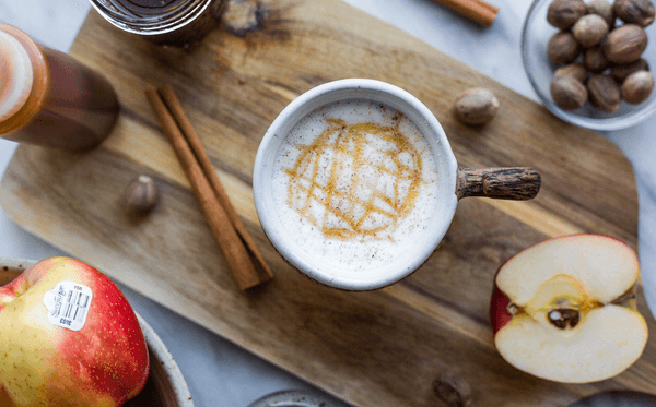 An Apple Crisp Macchiato on a cutting board with spices and apples.