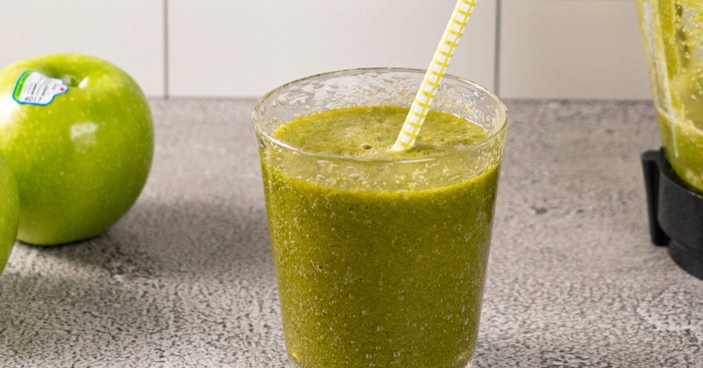 a glass with the sour green apple smoothie and a straw