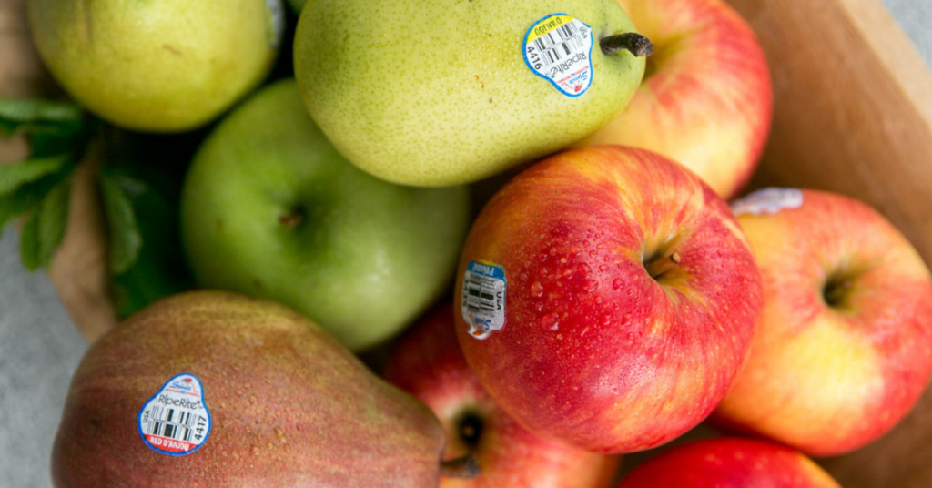 A mixed fruit bowl of apples and pears with stickers