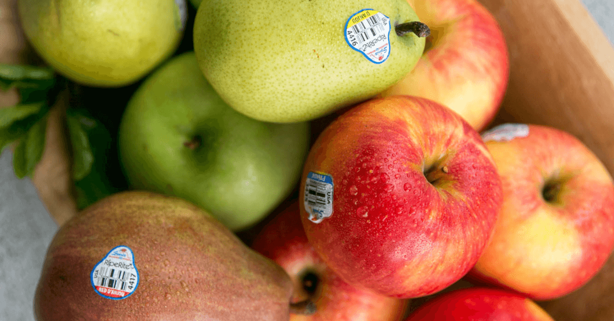 A mixed fruit bowl of apples and pears with stickers