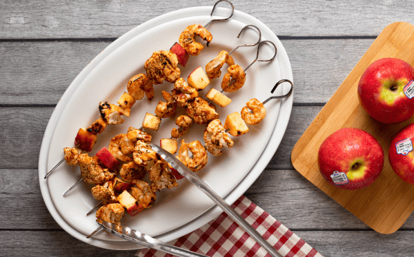 BBQ shrimp skewers with apple and cauliflower on a plate.