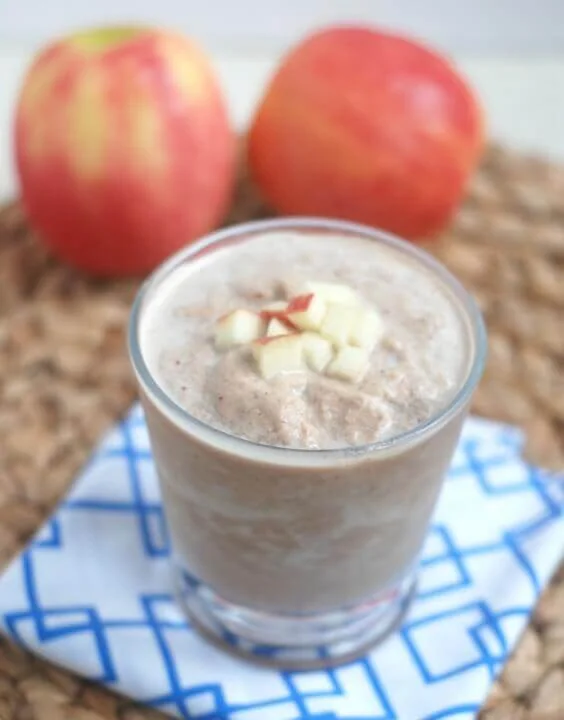 Chocolate peanut butter apple recovery smoothie with apple pieces on top.