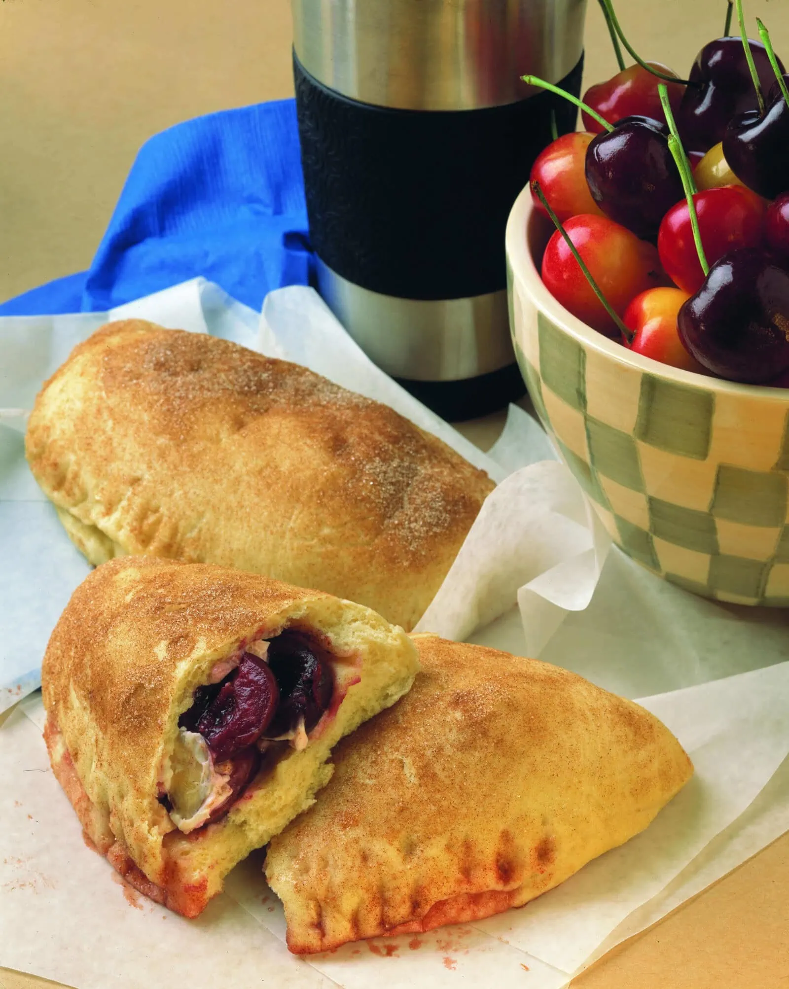 Cherry calzone with fresh cherries and a coffee cup on a table.