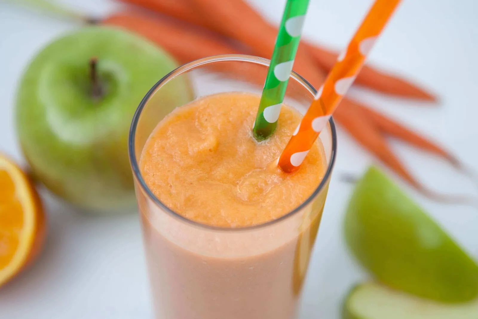 Fresh apple and carrot smoothie with straws, healthy fruit drink.