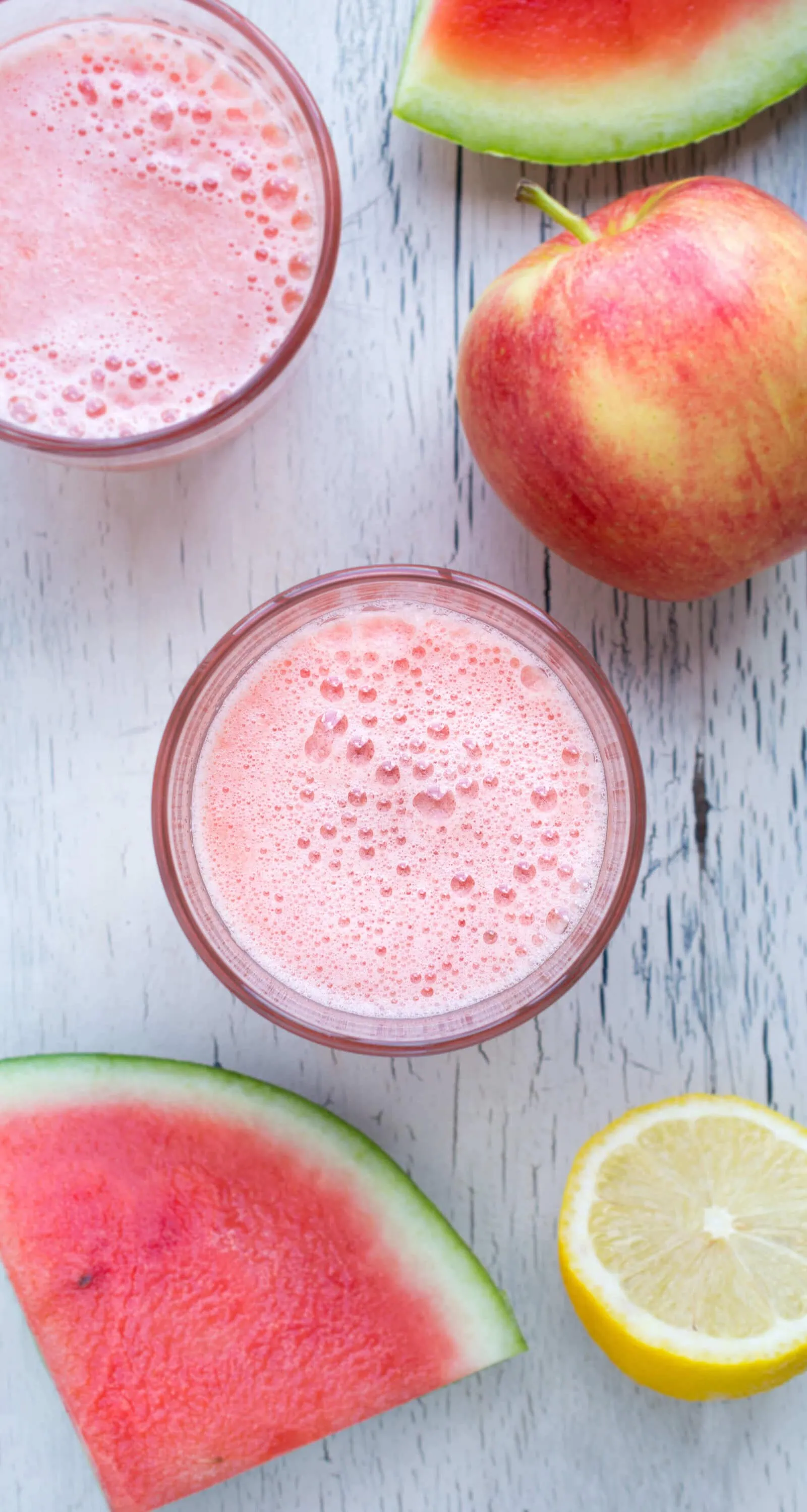 Refreshing watermelon juice with apples and lemon on a white wooden surface.