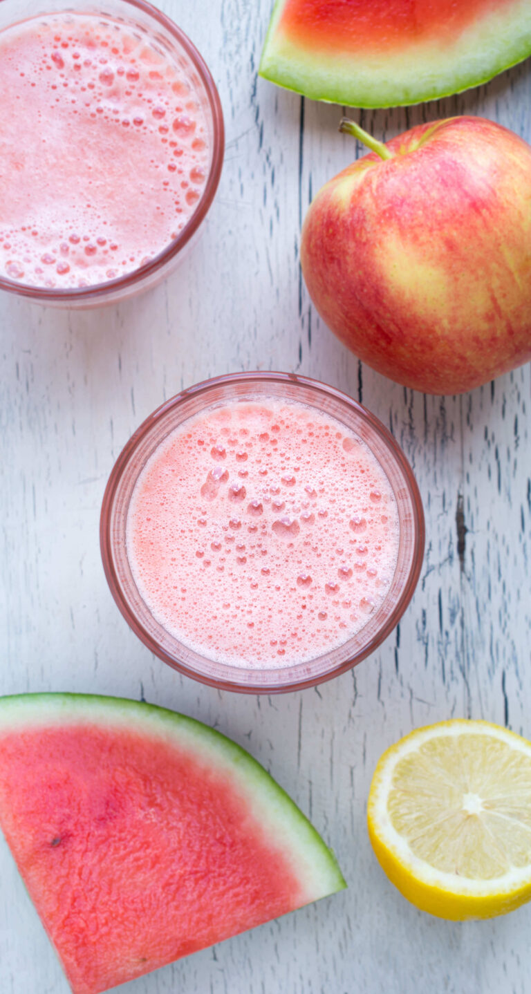 Refreshing watermelon juice with apples and lemon on a white wooden surface.