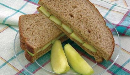 Peanut butter and apple sandwich with fresh apple slices on a plate.