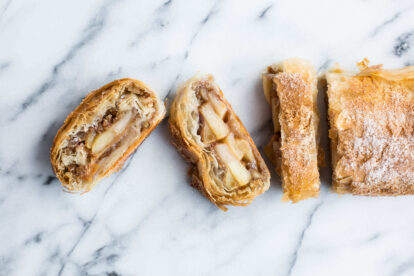 Apple strudel with phyllo dough and apple filling on marble surface.