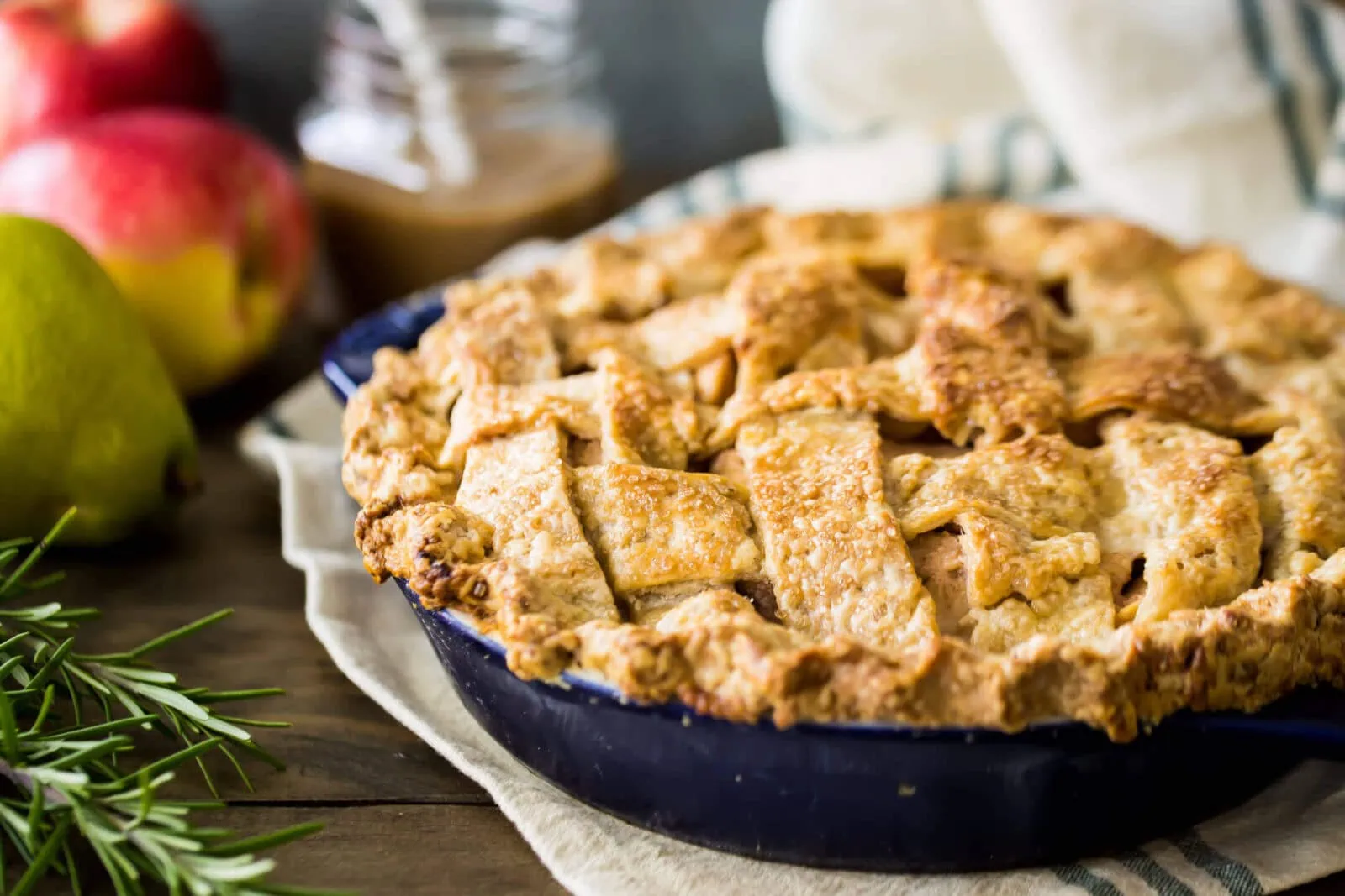 Freshly baked apple and pear pie in a dark blue pie dish on a rustic wooden table.