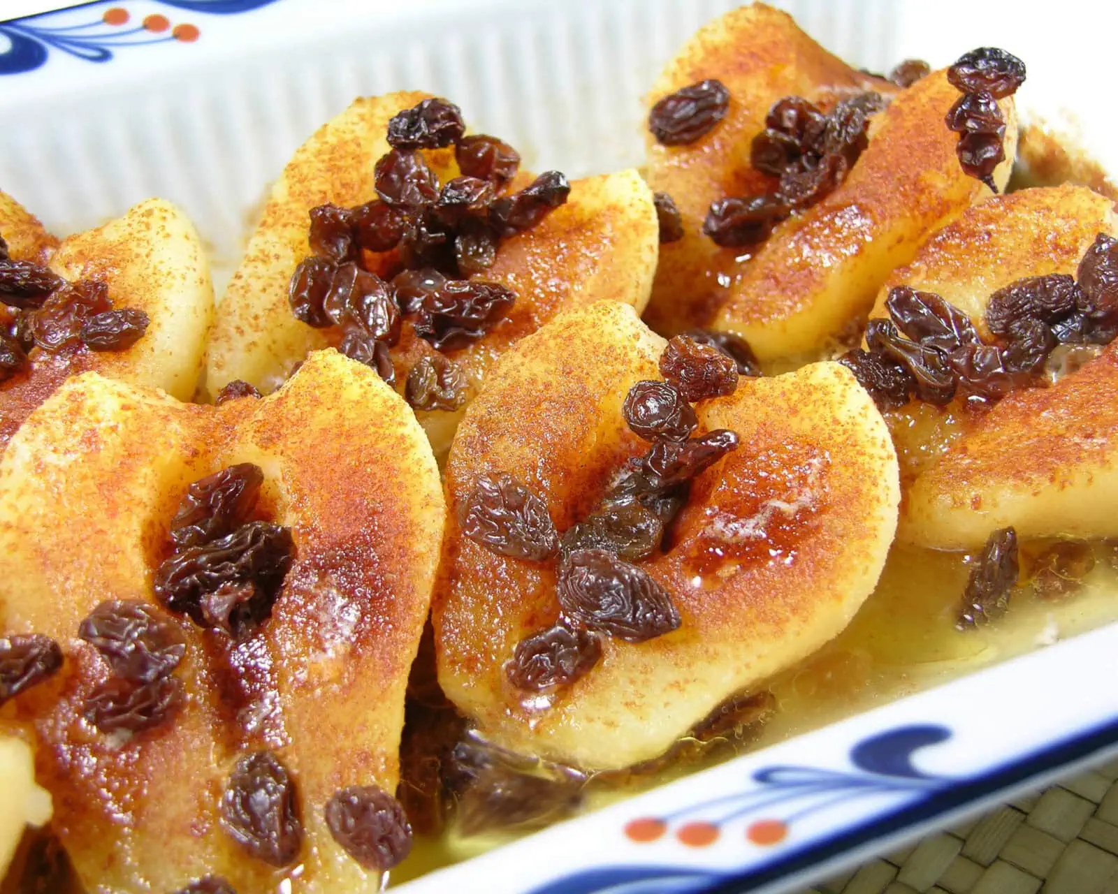 Baked pears topped with raisins served on a decorative dish for a healthy dessert.