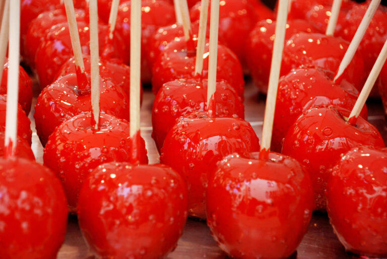 Close-up of shiny red candy apples with sticks, ready to eat.