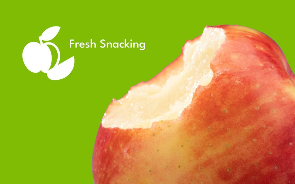 Close-up of a bitten ripe Ambrosia apple on a green background with Stemilt logo.