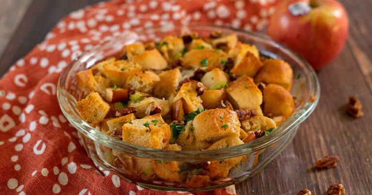 Granny Smith apple and pecan stuffing in a glass bowl on a wooden table.
