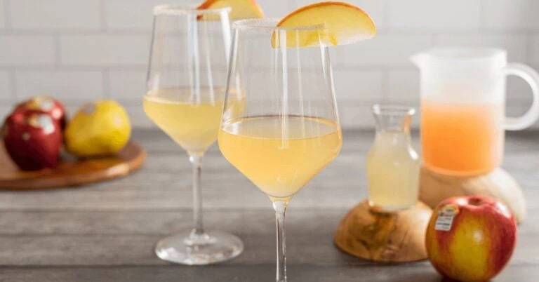 Apple and pear mimosas with fresh fruit on a wooden table.