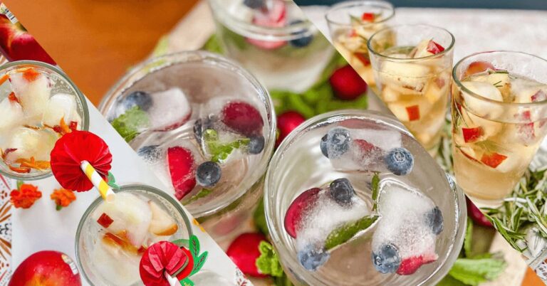 Colorful fruit ice cubes in glasses with berries and herbs for refreshing summer drinks.