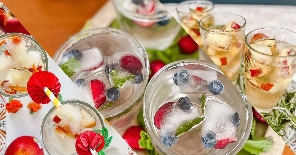 Colorful fruit ice cubes in glasses with berries and herbs for refreshing summer drinks.