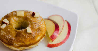 Baked apple donuts with apple slices on a white plate for healthy snack.