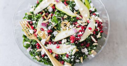 Fresh kale salad with pears, pomegranate seeds, goat cheese, and almonds.
