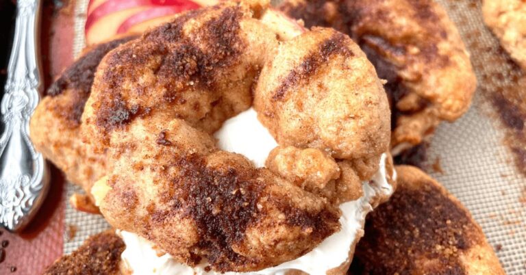 Close-up of a cinnamon sugar bagel with cream cheese on a baking sheet.
