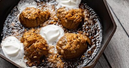 Baked Hasselback pears with oats, whipped cream, and caramel sauce in a skillet.